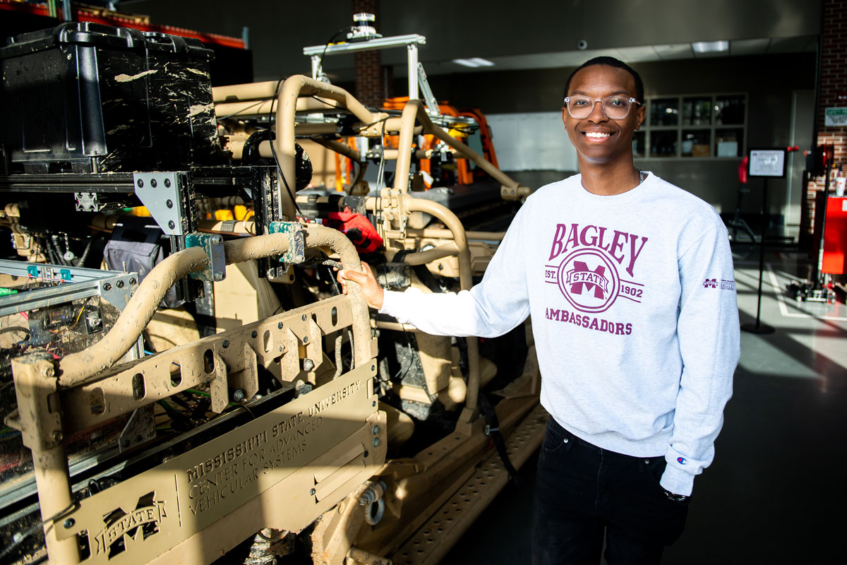 Jeffery Greer MSU Engineering student standing beside parts that he is going to school to learn how to build and design