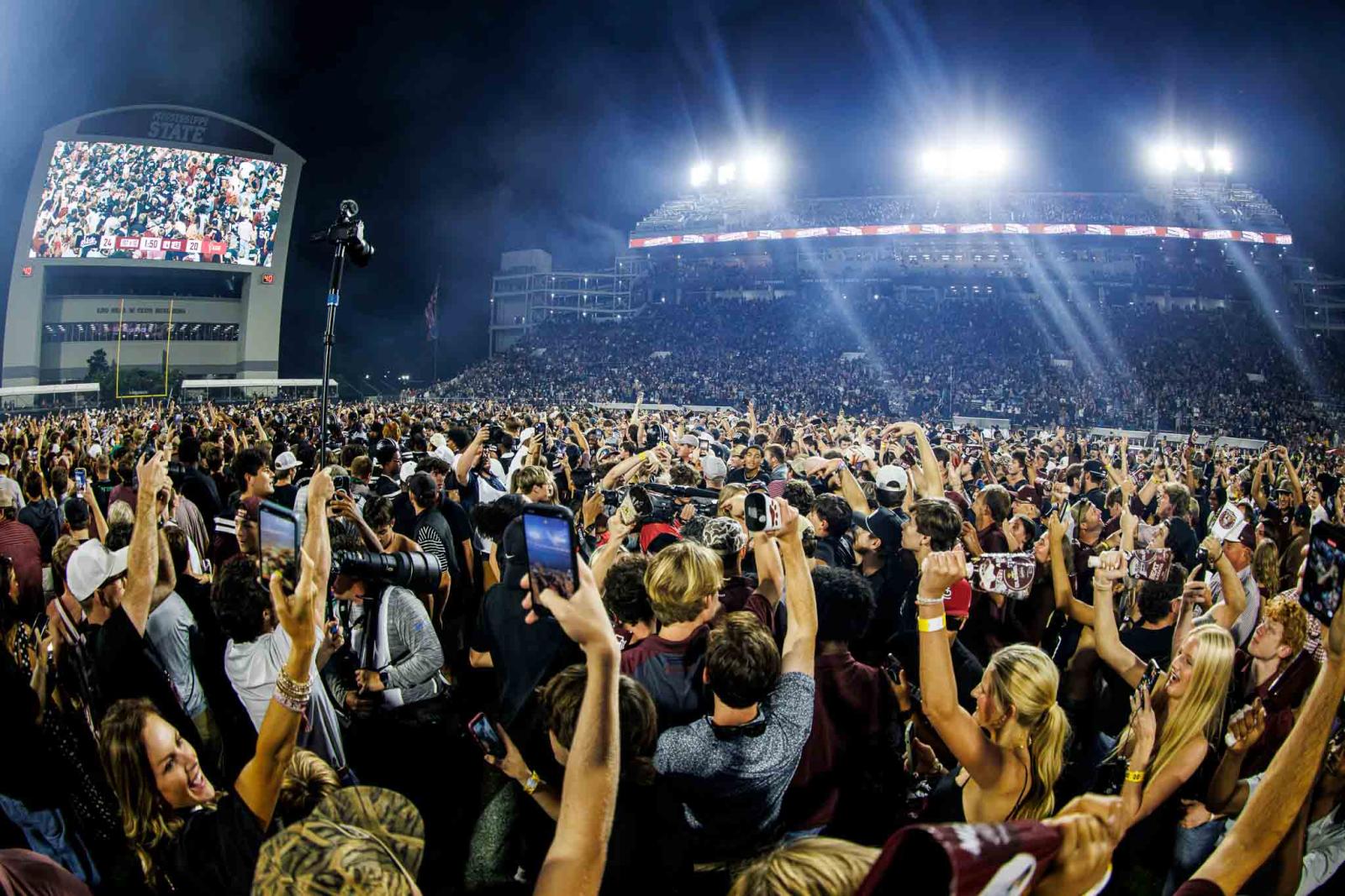 People filling the field of Davis Wade Stadium rushing the field after beating a ranked opponent.