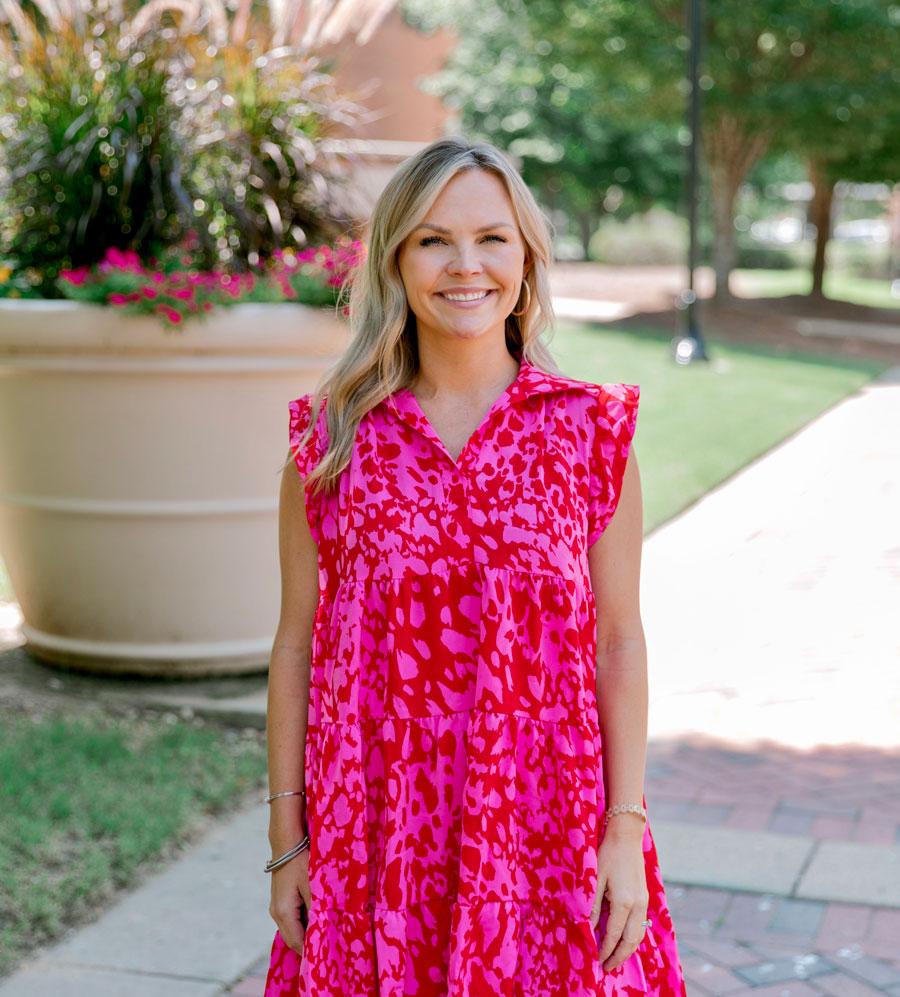 Admissions Counselor Lauren Porter smiling in front of McCool Hall in a pink dress