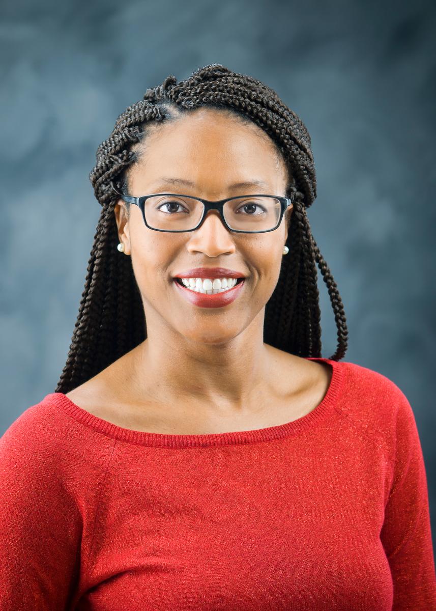 Portrait of Shwanda Jenkins with dark hair and glasses wearing a red top. 