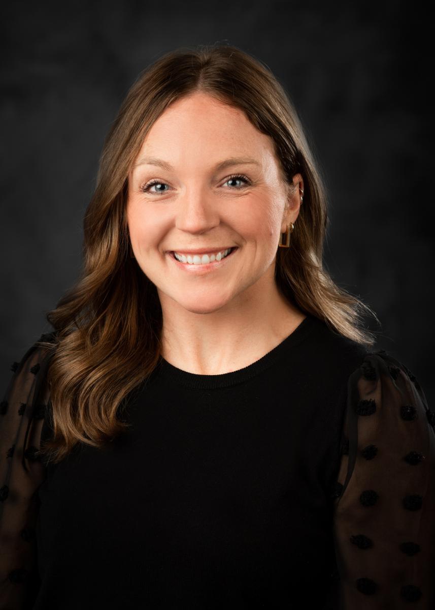 Portrait of Sally Rutland with short dark hair wearing a black shirt. 