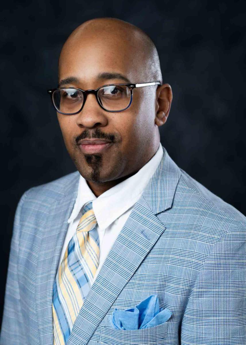 Mississippi State University professional headshot of a man with glasses wearing a blue blazer. 